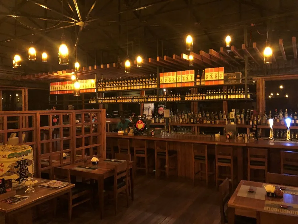 Warmly lit Yujo izakaya interior with a bar and dining tables